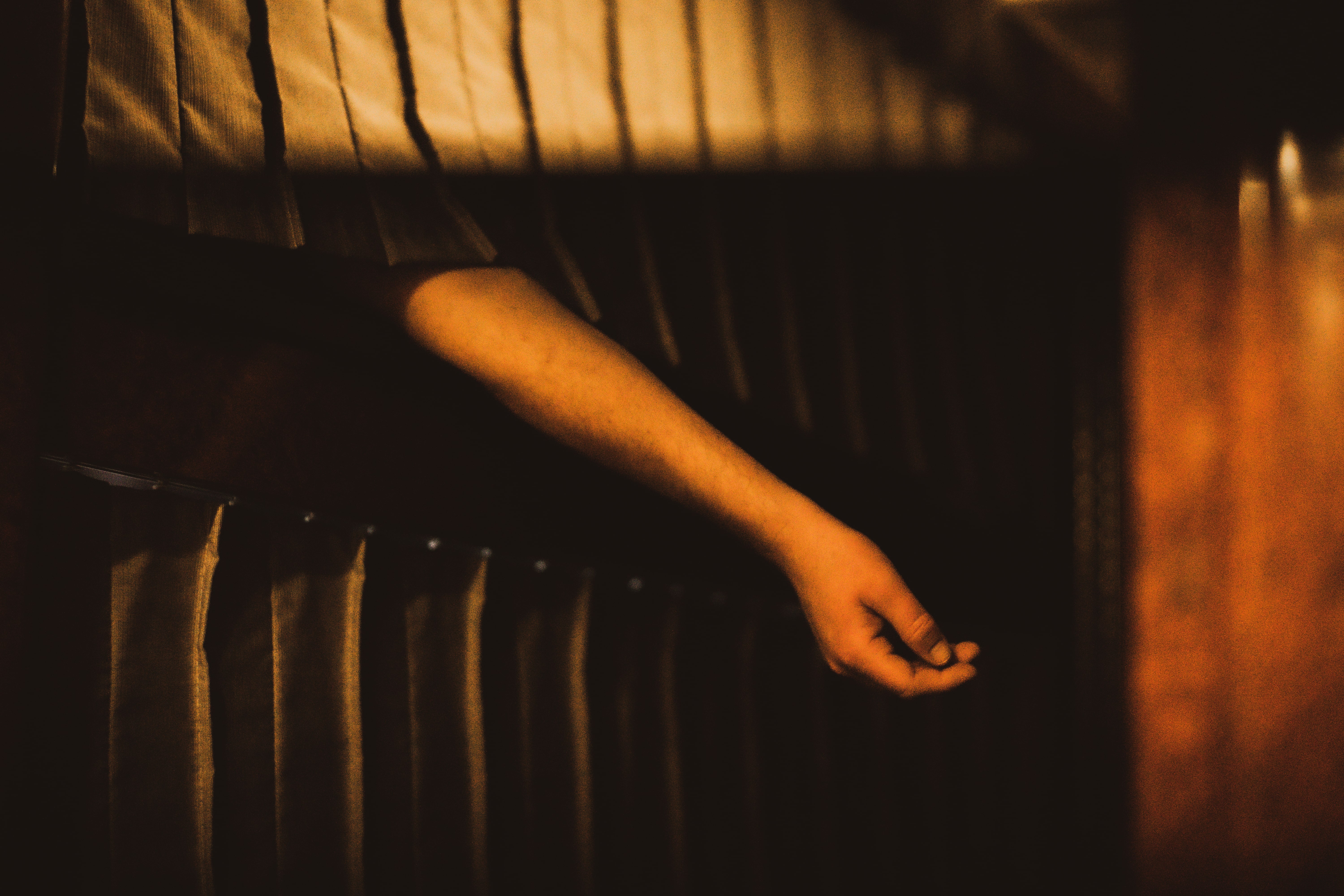 A photo of an arm hanging from beneath the curtain of a train cabin's bunk bed. 